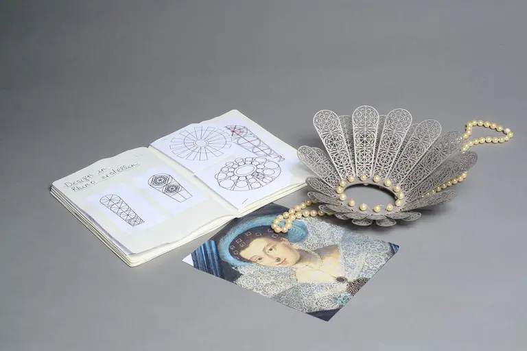 An open sketchbook featuring design drawings lies next to a decorative metal dish with an intricate pattern and pearls. Below is a color photo of a woman in historical attire. The composition emphasizes the relationship between art design and fashion history.