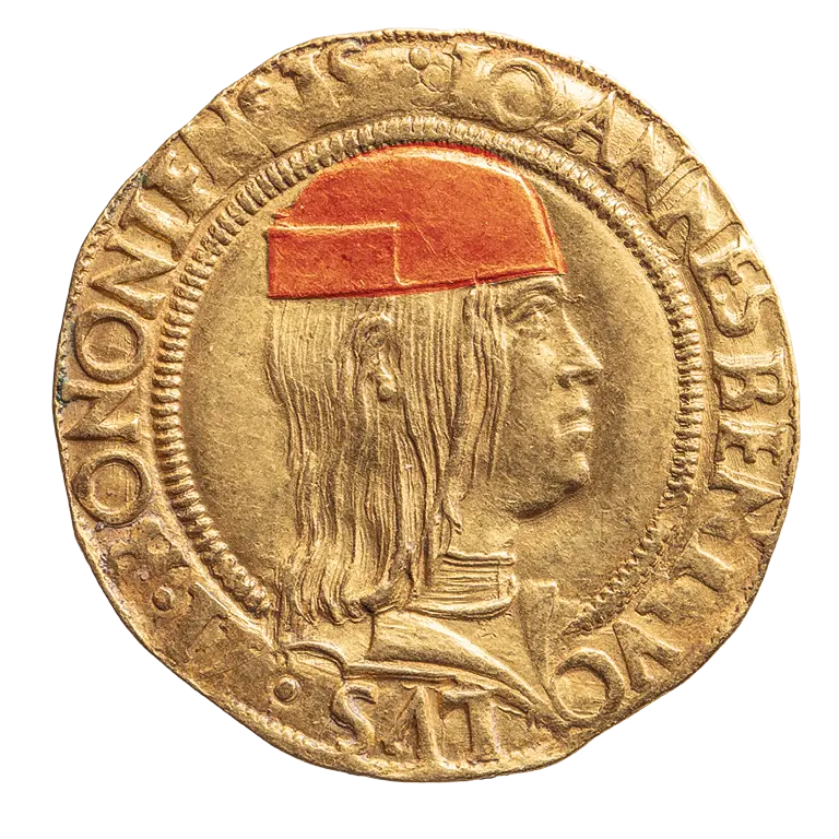 A gold coin featuring a profile of a man with long hair, wearing a red cap. Surrounding the image is engraved text, likely indicating the name and title associated with the figure. The coin has a smooth surface and a distinct circular shape.