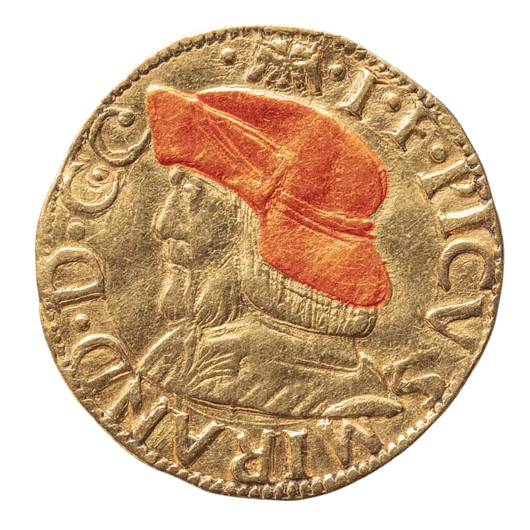 A golden coin features a profile of a man wearing a distinct red hat. The text around the edge identifies the coin, possibly indicating its historical significance. The overall design highlights the craftsmanship of the coin.