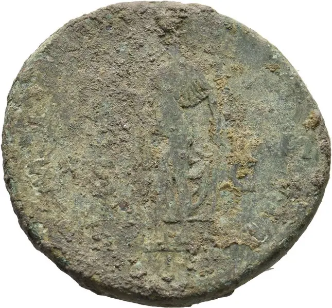 Das Bild zeigt eine stark abgedrehte Münze, die eine Figur darstellt. Die Details sind durch den Alterungsprozess und den Schmutz kaum erkennbar, aber die Umrisse sind noch zu erkennen. Die Münze hat eine runde Form und ist nicht perfekt glatt.