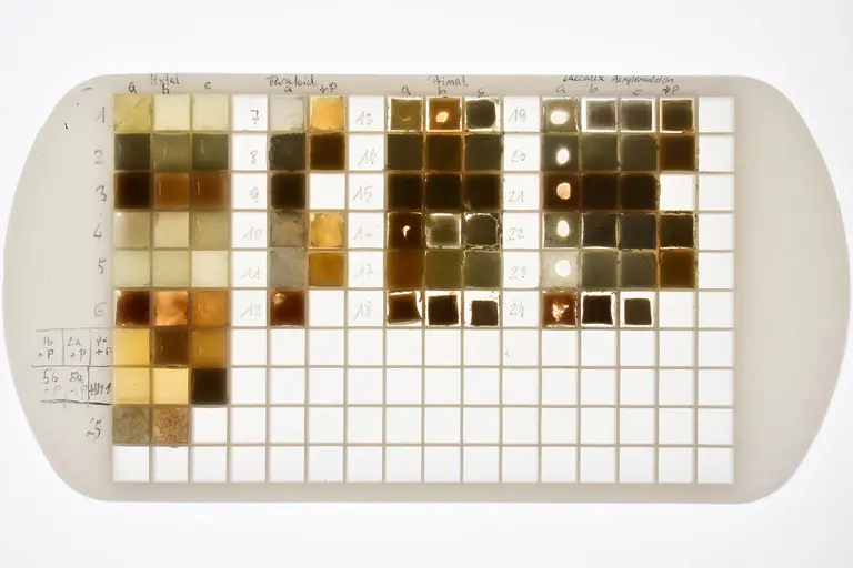 Eine Tabelle mit kleinen quadratischen Farbmuster-Kästen in verschiedenen Erdtönen und Brauntönen. Jede Reihe und Spalte ist beschriftet, um die einzelnen Farben zu identifizieren. Die Muster dienen zur Darstellung von Farbvariationen für eine Analyse oder Vergleich.