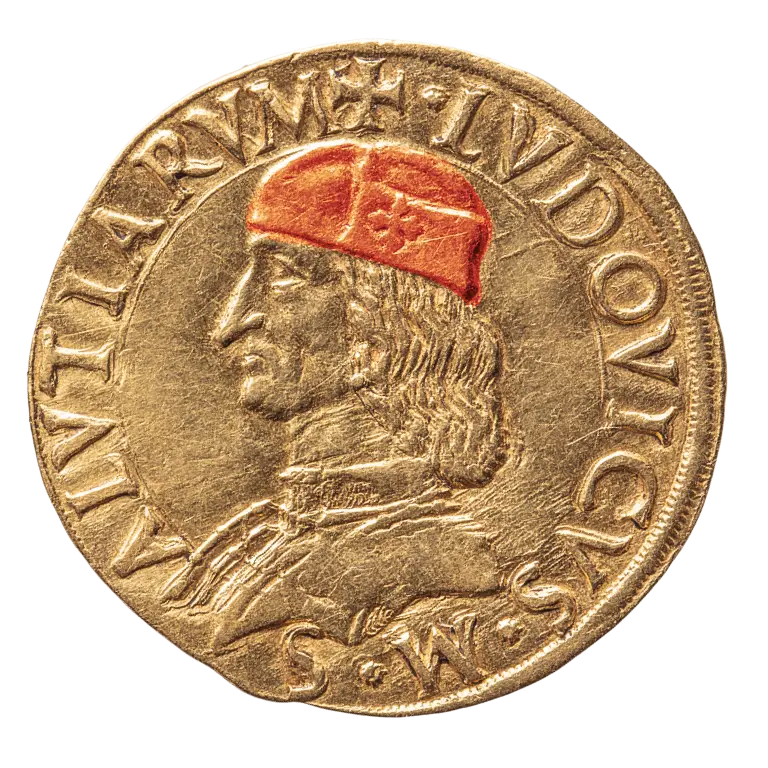 A gold coin featuring a profile of a man with long hair, wearing a red cap. The inscription surrounds the image, likely indicating the coin's origin or denomination. The overall design reflects historical currency, showcasing intricate detailing typical of older minted coins.