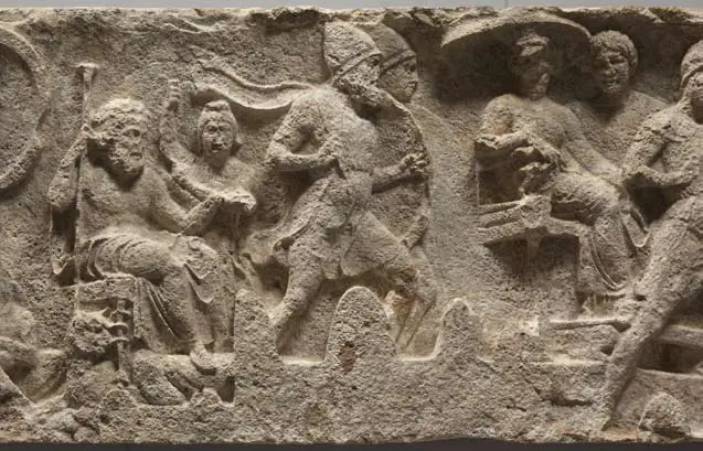 Die Abbildung zeigt ein Relief mit mehreren Figuren. Auf der linken Seite sitzt eine Person mit einem Stab, während andere in dynamischer Pose stehen oder laufen. Im Hintergrund sind zusätzlich weitere Figuren dargestellt, was auf eine Szene aus der Antike hinweist.