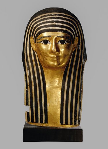 Ägyptische Mumienmaske mit goldener Oberfläche und charakteristischen schwarzen Streifen. Die Maske zeigt ein stilisiertes Gesicht mit großen Augen und einer klassischen Frisur, die an das alte Ägypten erinnert. Ein Teil ist beschädigt, aber die Details sind gut erhalten.