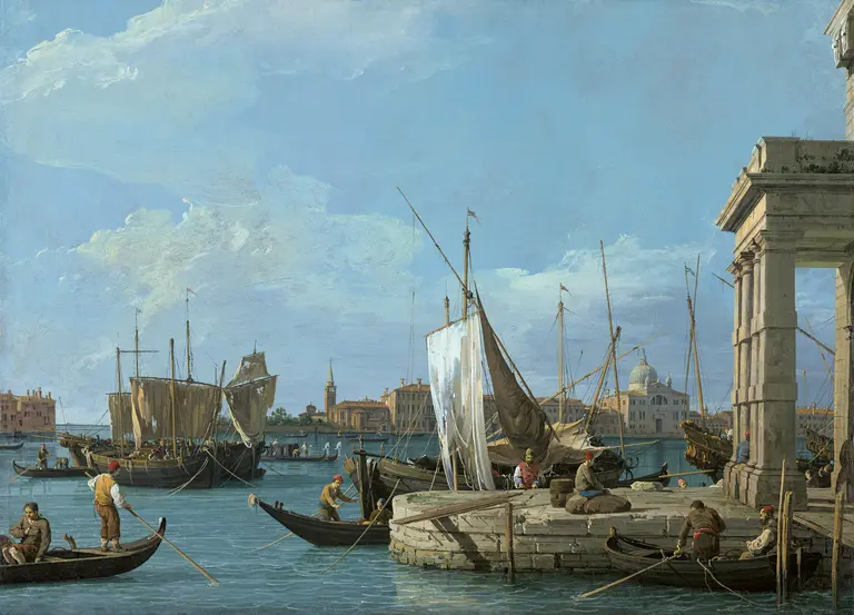 Ein malerischer Hafen mit mehreren Booten und Schiffen. Fischer arbeiten am Ufer, während Segelboote im Wasser liegen. Im Hintergrund sind Gebäude und ein klarer Himmel mit wenigen Wolken zu sehen.