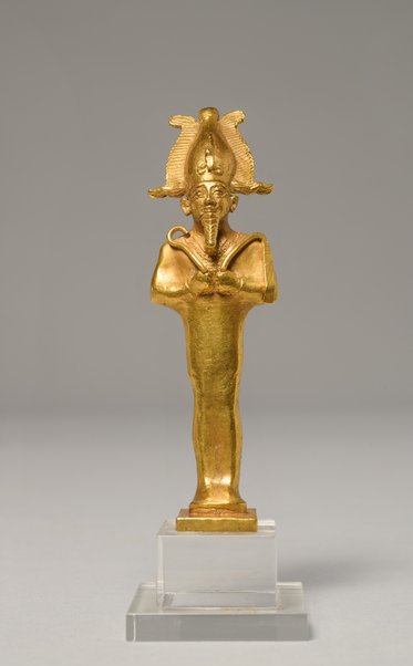 Eine goldene Statue eines ägyptischen Gottes mit einer gefalteten Haltung und Kopfschmuck. Die Figur steht auf einem transparenten Sockel. Der Kopf des Gottes ist von einem Uraeus (Kobra) umgeben, was seine Macht symbolisiert.