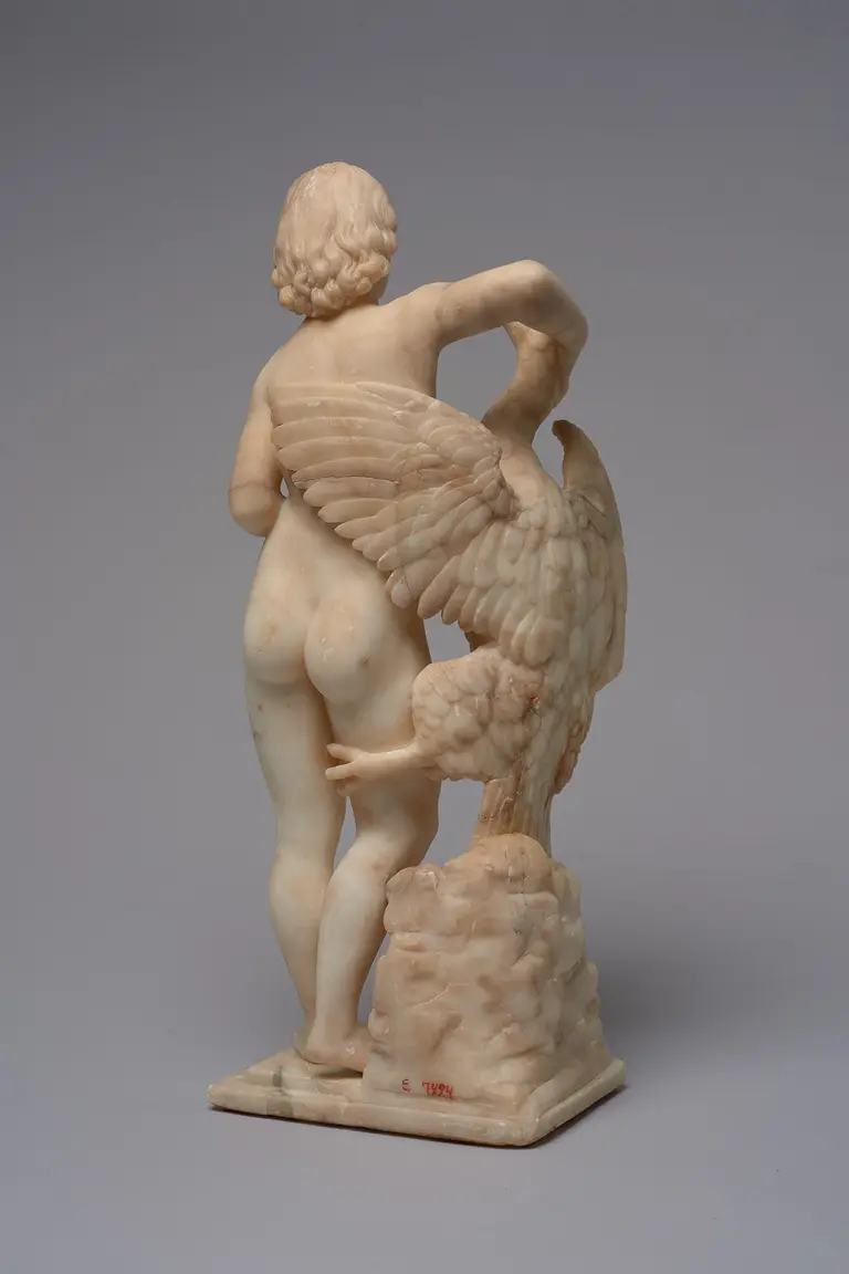 Eine alabasterne Skulptur zeigt eine nackte menschliche Figur mit dem Rücken zur Ansicht. Die Figur hat lockiges Haar und ist halb zur Seite gedreht. Neben ihr steht ein geflügeltes Wesen, das ihren Arm berührt und dabei eine aufrechte Position einnimmt.