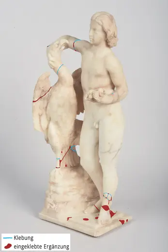 Die Skulptur zeigt eine nackte, männliche Figur, die einen Vogel hält und mit dem anderen Arm eine Statue oder einen Sockel greift. Die Oberfläche ist teilweise mit Hinweisen zur Restaurierung markiert, die Klebungen und Ergänzungen anzeigen.