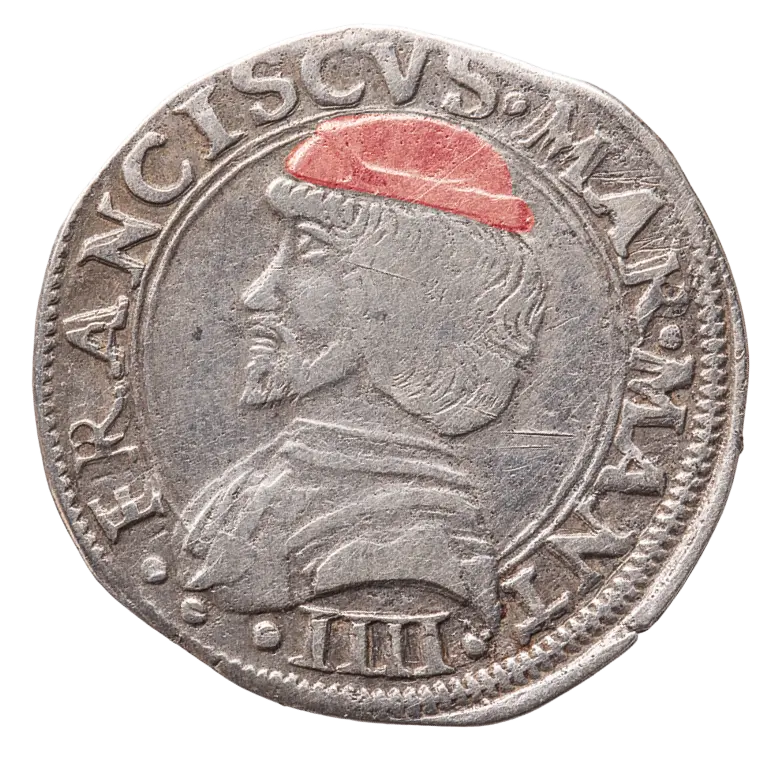 A silver coin features a profile of a man wearing a red cap, with the inscription 