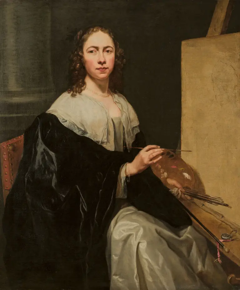 A woman with curly hair sits in a chair, holding a palette of paints in one hand and paintbrushes in the other. She wears a dark shawl over a light dress, with a neutral background that suggests an artist's studio.