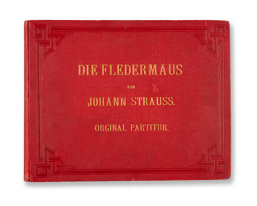Ein rotes Buchcover mit goldener Aufschrift. Darauf steht „Die Fledermaus von Johann Strauss. Original Partitur.“ Das Design ist schlicht, mit dekorativen Randmotiven.