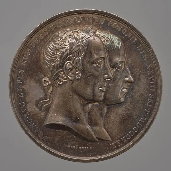 Die Abbildung zeigt eine Bronze-Medaille mit zwei Profilen von Männern, die sich einander zuwenden. Über den Köpfen steht eine Inschrift. Die Medaille ist detailliert gestaltet und besitzt eine glänzende Oberfläche.