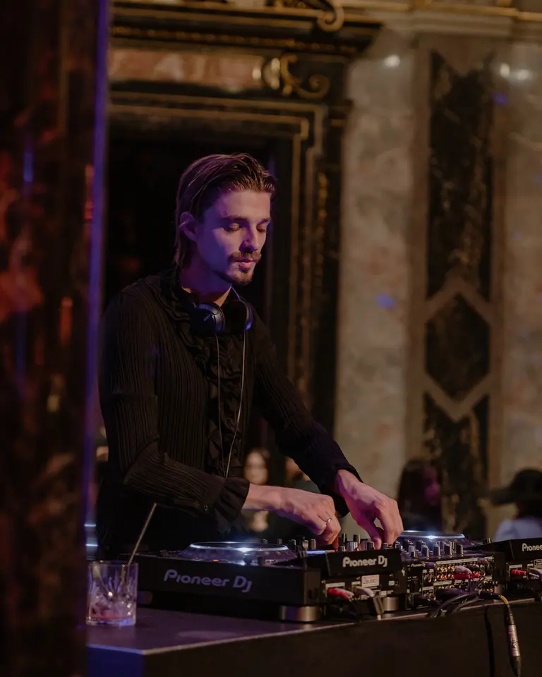 A DJ is focused on mixing music at a turntable. 