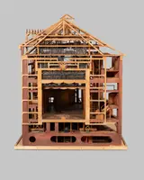 Das Bild zeigt ein detailreiches Modell eines Hauses, das aus Holz gefertigt ist. Die Struktur ist offen, sodass Raumaufteilung und Innenarchitektur sichtbar sind. Es sind Treppen, Fenster und dekorative Elemente erkennbar, die das Design des Gebäudes verdeutlichen.