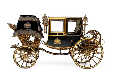 Die Abbildung zeigt eine kunstvoll verzierte Kutsche mit goldenen und schwarzen Elementen. Sie verfügt über große Räder, seitliche Lampen und ein elegantes Dach mit einem königlichen Emblem. Die Kutsche vermittelt einen Eindruck von historischer Pracht und Luxus.