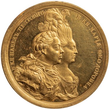 Eine goldene Medaille mit zwei Seitenprofilen von einem Mann und einer Frau. Der Mann trägt aufwendige Kleidung, während die Frau eine hohe Frisur hat. Um die Figuren herum befinden sich russische Schriftzeichen.