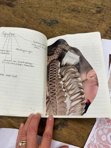 A person’s hand holds an open notebook featuring handwritten notes on the left page and a photo collage on the right. The collage depicts intricate fabric textures, possibly related to fashion or design, highlighting fine details and craftsmanship.