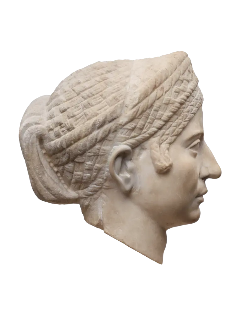 Das Bild zeigt einen antiken Marmorkopf einer Frau im Profil, mit detaillierter Frisur und Gesichtszügen. Der Kopf ist sorgfältig bearbeitet und zeigt eine Binde im Haar. Die Statue vermittelt einen Eindruck von historischer Kunstfertigkeit und Stil.