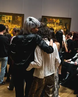 Two people stand in the Picture Gallery observing several artworks.