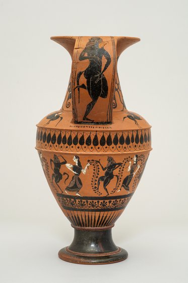 Eine antike griechische Vase mit einem bunten Design. Die Vase zeigt eine Figur in einem dynamischen Posing auf dem Hals und mehrere Figuren, die auf der unteren Seite tanzen oder musizieren. Die Farbgebung umfasst überwiegend Schwarz und Orange, typisch für die griechische Vasenmalerei.