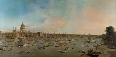 Ein Panorama eines Flusses mit vielen Booten. Im Hintergrund ist eine Stadt mit einer großen Kathedrale zu sehen. Der Himmel ist klar und zeigt verschiedene Blautöne. Die Szene vermittelt eine lebendige, geschäftige Atmosphäre am Wasser.