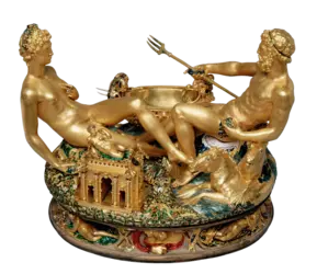 Eine kunstvoll verzierte Skulptur zeigt zwei goldene, nackte Figuren, die auf einem reich ornamentierten Sockel sitzen. Die Figuren stellen mythologische Charaktere dar und sind von Pflanzen und Tieren umgeben. Im Hintergrund ist eine kleine Architektur zu sehen, die den Gesamteindruck ergänzt.