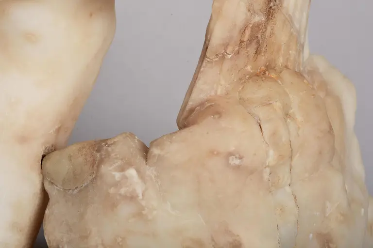 Ein close-up Bild von zwei in sanften, hellen Farbtönen gehaltenen Steinskulpturen. Die Textur ist glatt, mit sichtbaren Adern und natürlichen Unregelmäßigkeiten, die den organischen Eindruck der Formen verstärken. Die Skulpturen scheinen menschliche Körperteile darzustellen, jedoch ohne klare Details.