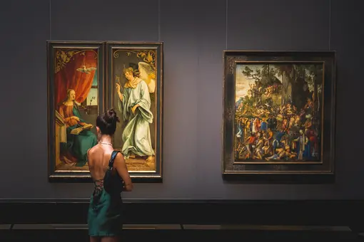 A woman stands before two paintings in the Picture Gallery of the Kunsthistorisches Museum. 