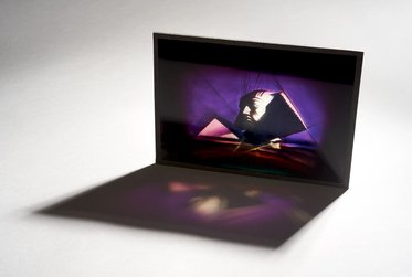 Eine aufgestellte, rhombusförmige Struktur zeigt ein Spiel von Licht und Schatten in lila und orangefarbenen Tönen. Im Vordergrund ist eine schattenhafte Darstellung eines Gesichts oder Profils sichtbar. Die Komposition vermittelt eine künstlerische und mysteriöse Stimmung.