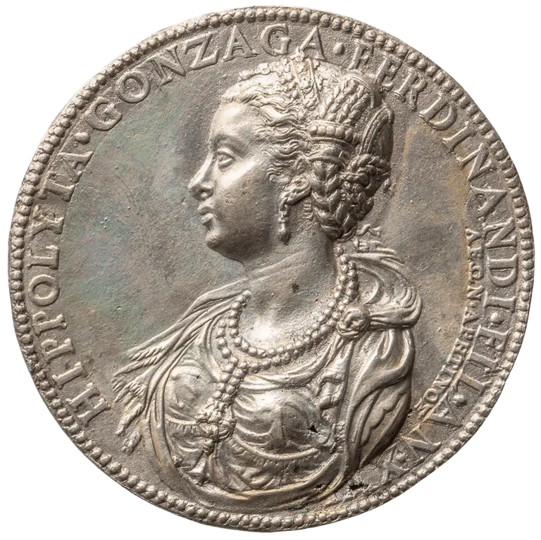 A silver coin featuring the profile of a woman adorned with elaborate jewelry and a hairstyle embellished with decorative elements. The inscription around the edge includes the name
