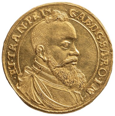 Eine goldene Medaille zeigt ein Porträt eines bearded Mannes im Profil. Der Mann trägt eine historische Kleidung und ist von einem runden Rand umgeben, auf dem Schriftzüge eingraviert sind.