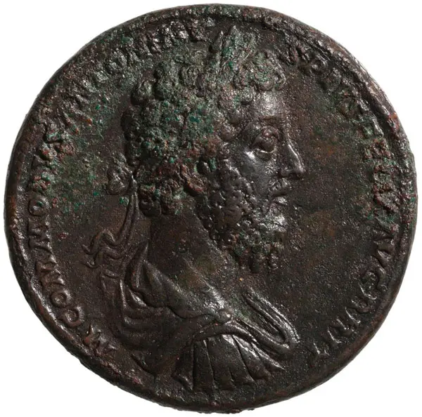 Eine antike Münze zeigt das Profil eines bärtigen Mannes mit lockigem Haar. Um ihn herum sind lateinische Beschriftungen zu sehen, die möglicherweise seinen Namen oder Titel angeben. Die Oberfläche der Münze ist antiquiert und zeigt Patina.