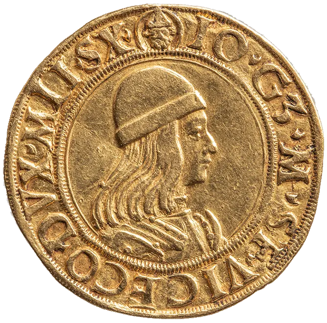A gold coin featuring the profile of a regal figure wearing a cap. The edge of the coin includes engraved text, likely representing a name or title. The overall design showcases intricate details typical of historical currency.