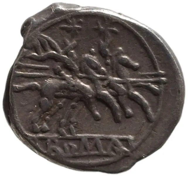 Eine alte Münze zeigt ein Relief von zwei Reitern, die auf einem Wagen gezogen von Pferden sitzen. Unter der Darstellung ist eine Inschrift zu sehen. Die Münze vermittelt ein Gefühl von historischer Bedeutung und Handwerkskunst.