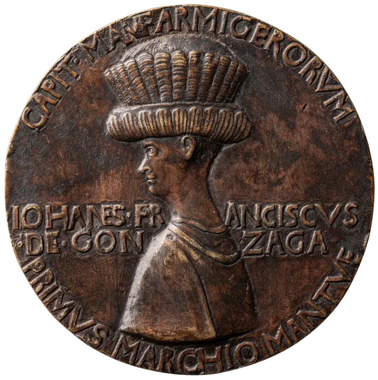 Bronze medallion featuring a profile of a man with a tall, intricately patterned hat. The text encircling the image includes names and titles, indicating his prominence. The overall design reflects historical significance and artistry.