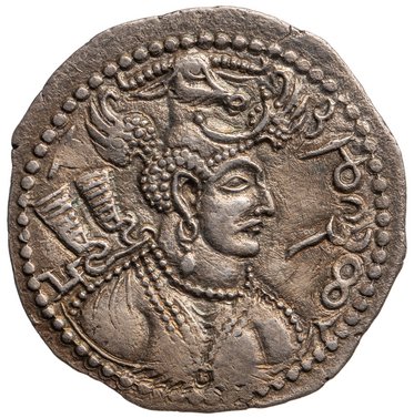 Eine silberne Münze mit einem Portrait eines Herrschers im Profil. Der Herrscher trägt einen mit einer Krone und Ornamenten geschmückten Kopfputz. Im Hintergrund sind dekorative Elemente und Details zu sehen, die die historische Bedeutung der Münze unterstreichen.