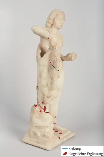 Eine marmorene Statue einer männlichen Figur, die in einer stehenden Pose dargestellt ist. Die Figur hält eine Hand an ihrem Oberkörper. An verschiedenen Stellen sind farbige Markierungen sichtbar, die auf Reparaturen und Ergänzungen hinweisen. Der Hintergrund ist einfach und neutral.