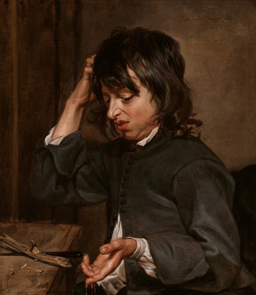 Ein junger Mann mit unrasiertem Gesicht und langen Haaren sitzt an einem Tisch, hält sich nachdenklich die Hand am Kopf und schaut auf seine offene Hand, in der kleine Gegenstände liegen. Der Hintergrund ist düster und aus Holz.