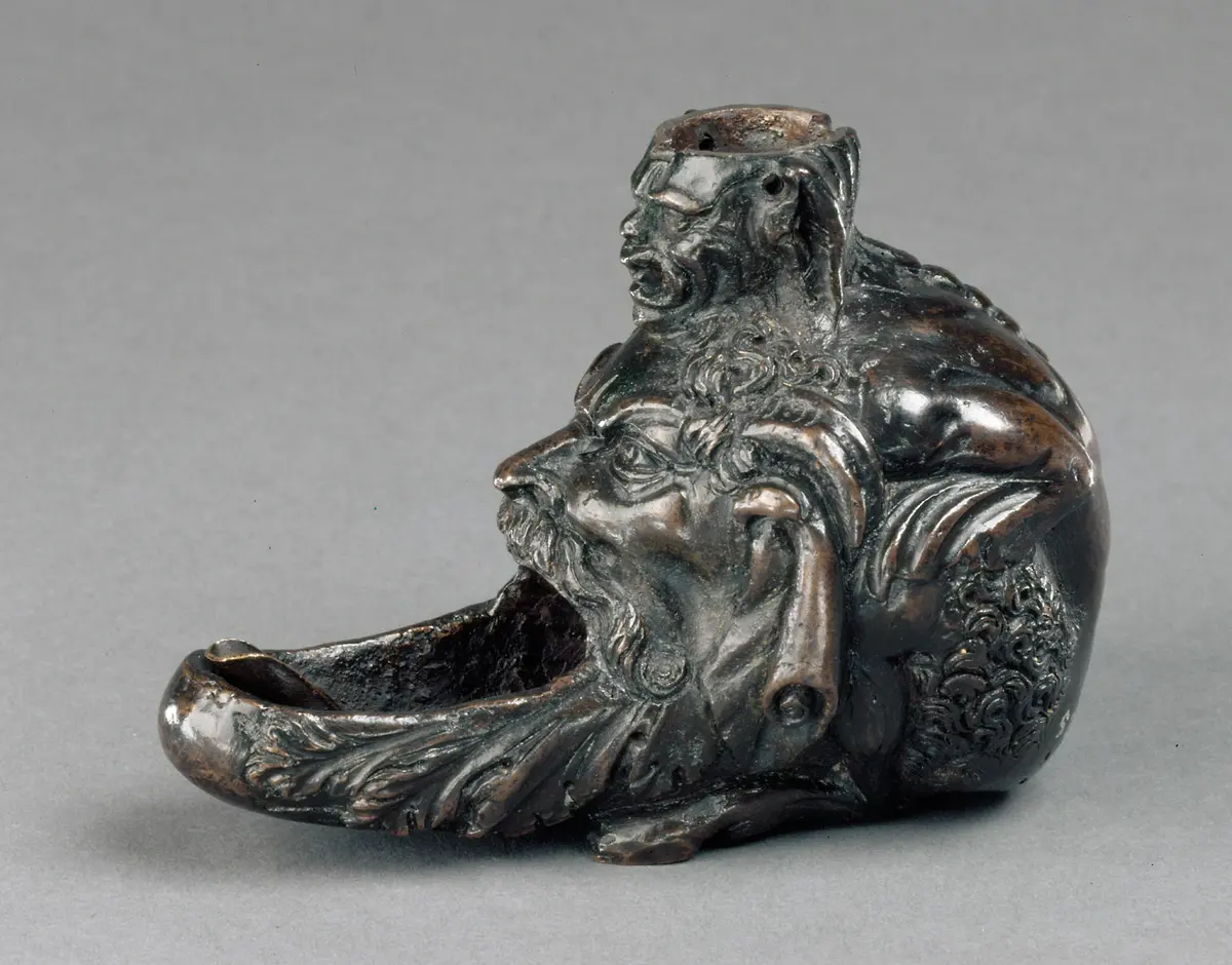 Öllampe in Gestalt eines hockenden Satyrs mit groteskem Maskeron zwischen den Knien
