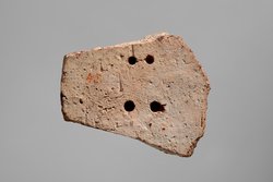 Fragment einer Aufsatzplatte(?) mit Darstellung von musizierenden Flügelfrauen in Ranken. Flügelfrau mit Kithara