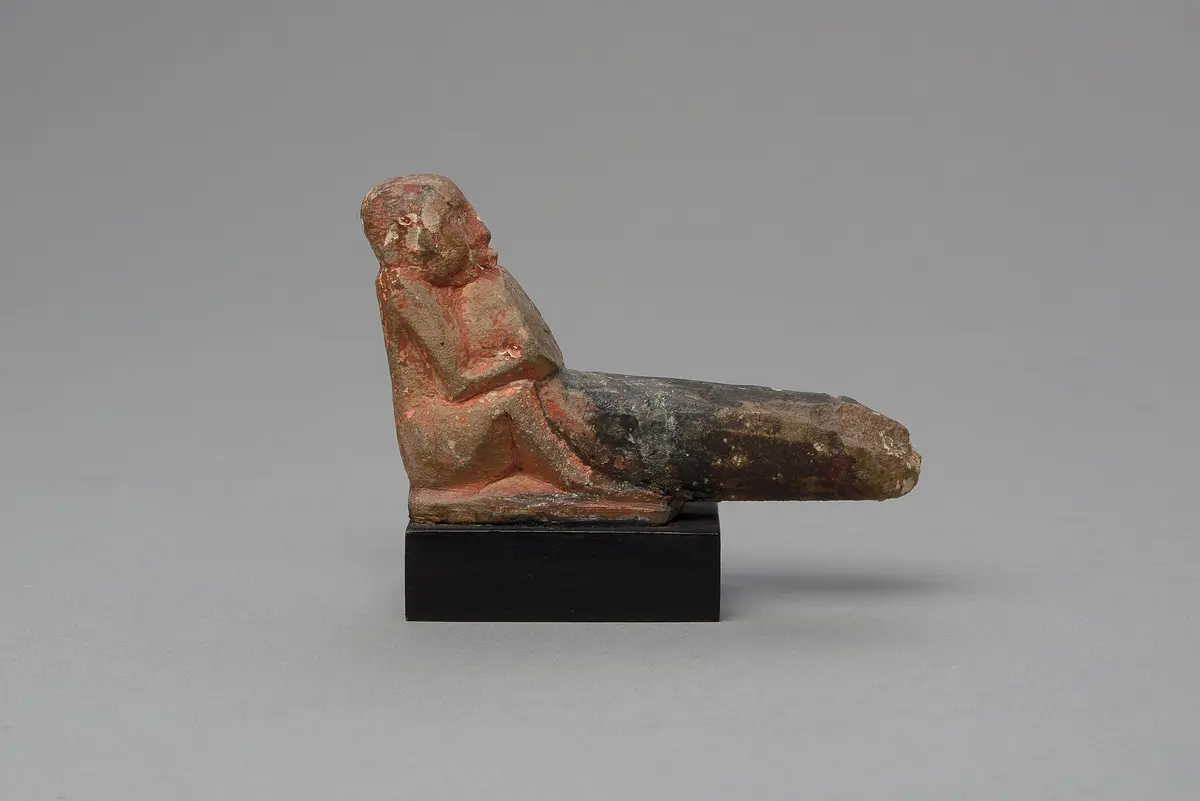 Hockender, nackter Mann mit übergroßem Phallus, eine Stele haltend