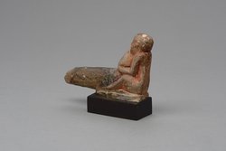 Hockender, nackter Mann mit übergroßem Phallus, eine Stele haltend