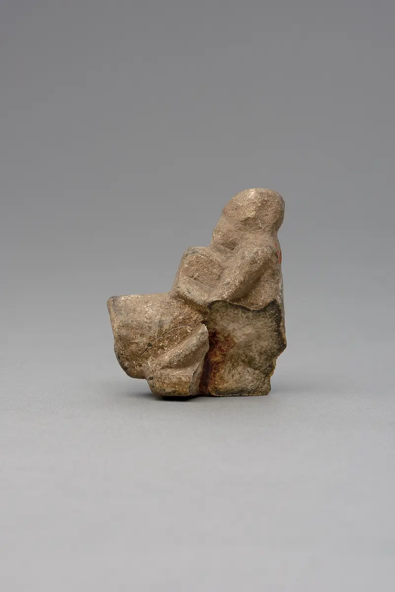 Hockender, nackter Mann, über seinem Phallus eine Stele haltend, fragmentiert
