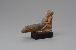 Hockender, nackter Mann mit übergroßem Phallus, eine Stele haltend