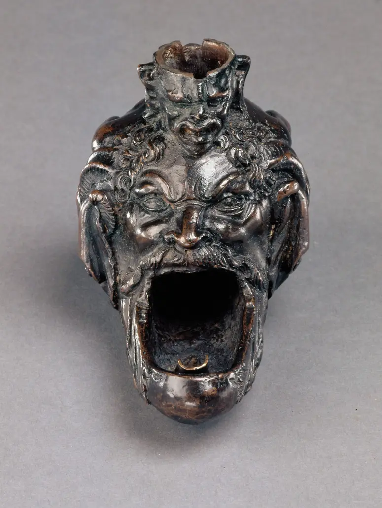 Öllampe in Gestalt eines hockenden Satyrs mit groteskem Maskeron zwischen den Knien