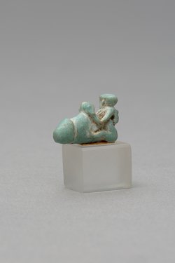 Mit ausgestreckten Beinen sitzender, nackter Mann mit übergroßem Phallus und Röhrentrommel