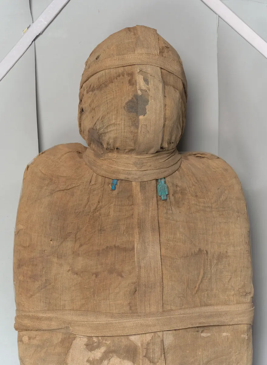 Mumie eines Mannes mit gut erhaltener Wickelung, am Hals zwei Amulette