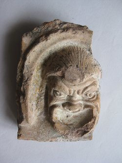 Fragment einer Krönung mit Theatermasken im Bogenfries: Maske und Teil eines Bogens