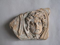 Fragment einer Krönung(?) mit Masken in schlangenförmig gewundenen Bändern: Gorgoneion