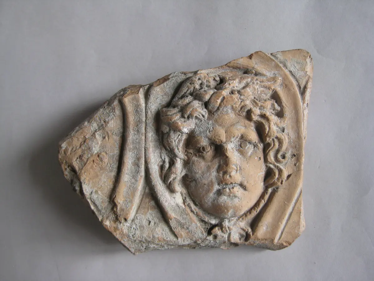 Fragment einer Krönung(?) mit Masken in schlangenförmig gewundenen Bändern: Gorgoneion
